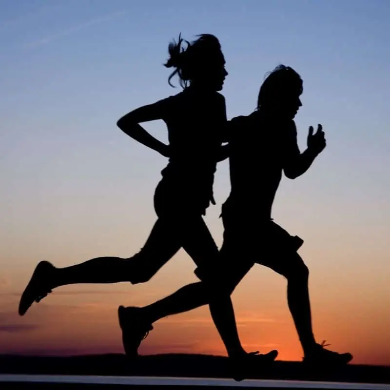 Man and woman running along sunset